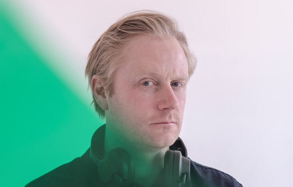 Headshot of AIAIAI co-founder Frederik Jørgensen. He is looking into the camera and has a pair of headphones around his neck. The image has been modified so that a wash of green covers the left side of the image and tints the appearance of his neck